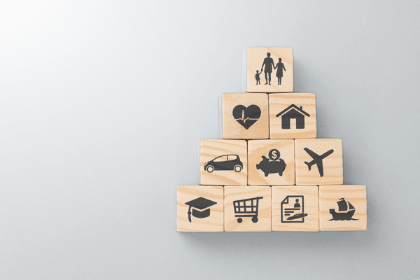 Grey background with 10 individual wooden blocks that have different pictures on each depicting different types of insurance. Family, health, home, auto, savings, travel, college, groceries, applications, boat.