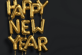 Happy New Year gold foil balloons in front of a black background