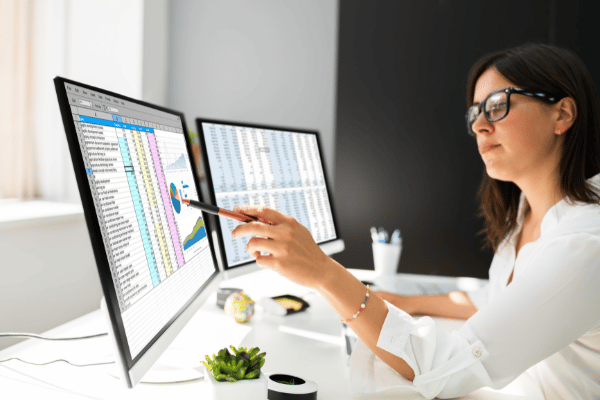 Female analyst looking at both her computer screens with reports pulled up