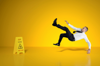 man slipping on a wet floor with a caution sign that says caution "wet floor"