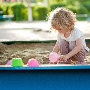 Girl playing by herself in sandbox