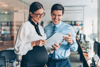Man And Pregnant Woman Reviewing Papers In An Office