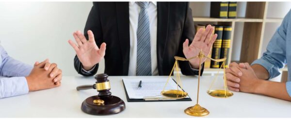 Three People In Conference With Gavel And Balance Scales On Table
