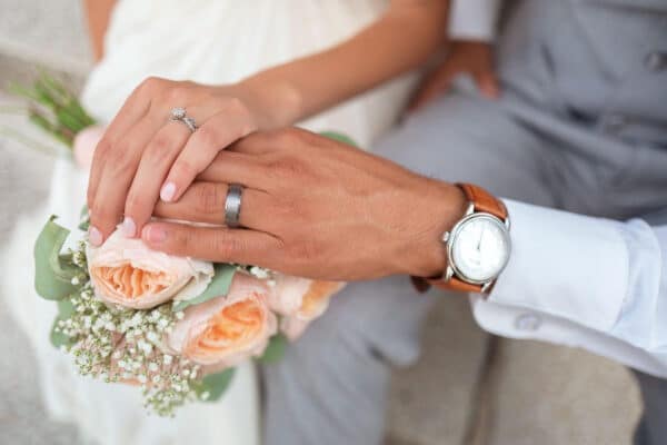 Wedding Photo Of Couple's Hands, Rings, And Bouquet