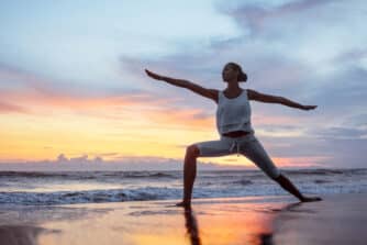Woman Doing Yoga On A Beach During Sunrise
